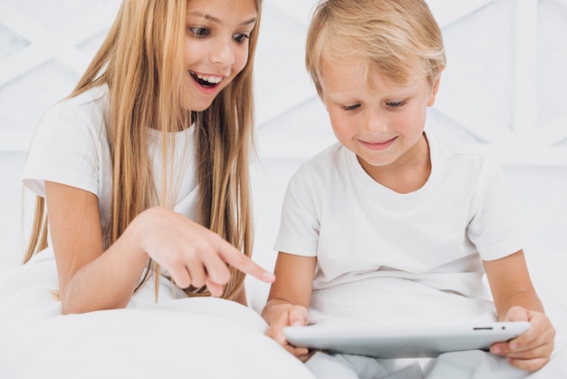 Irmãos assistindo algo engraçado em um tablet