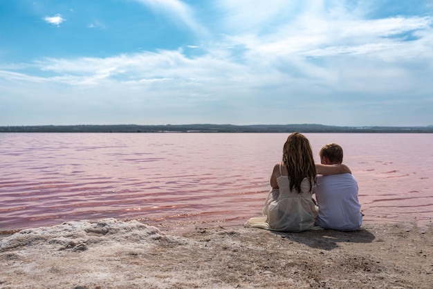 Irmãos bonitos adolescente sentado em uma costa do lago rosa incrível