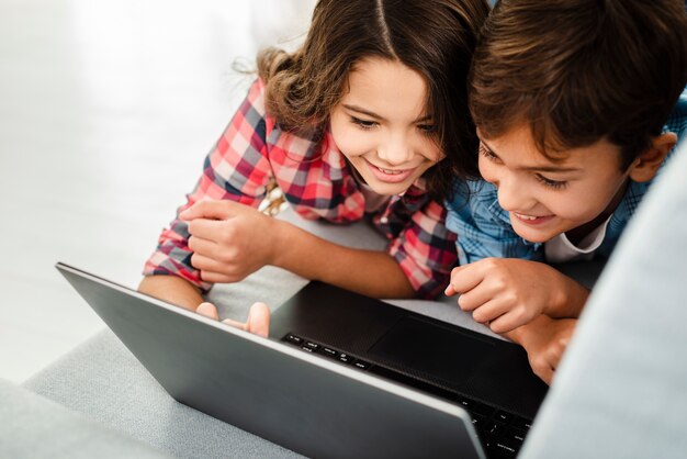 Irmãos de alto ângulo em casa usando laptop