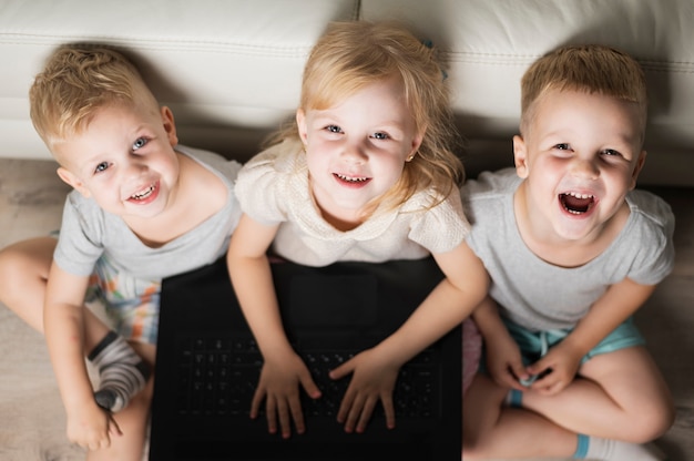 Irmãos de alto ângulo sorridente, jogando no laptop