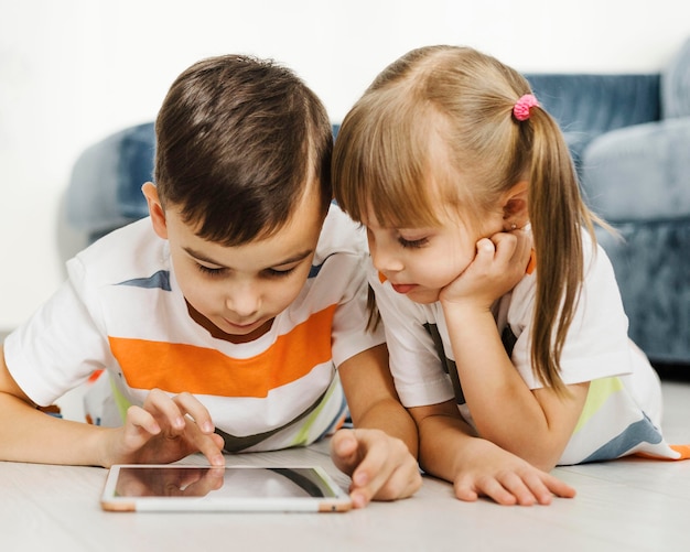 Irmãos de frente usando um tablet digital