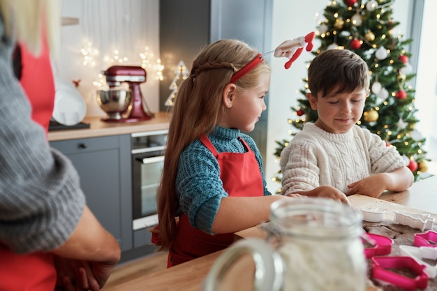 Irmãos fazendo biscoitos de gengibre em cozinha doméstica