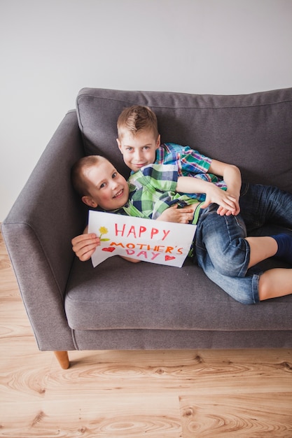 Irmãos felizes com cartaz para o dia de mãe