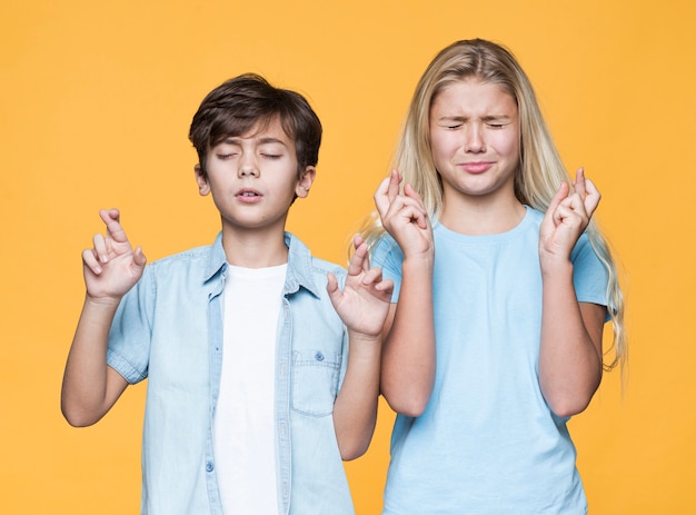 Foto grátis irmãos jovens fazendo desejos juntos