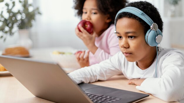 Irmãos ouvindo música e usando laptop