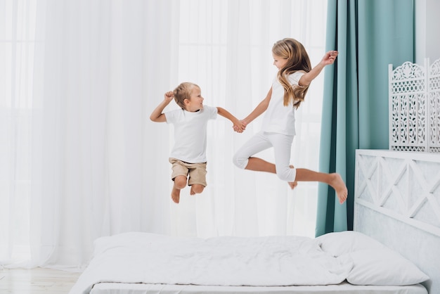 Irmãos pequenos pulando na cama