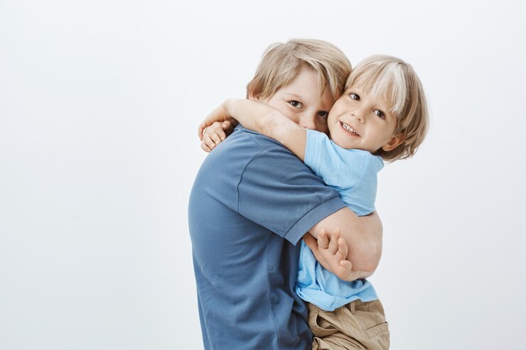 Foto grátis irmãos são melhores amigos. retrato de um menino europeu bonito abraçando o irmão e olhando, feliz por ter um irmão