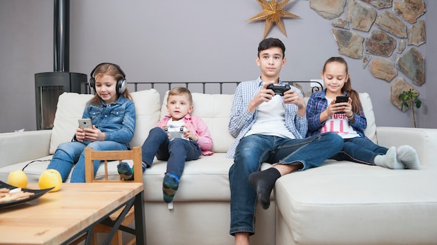 Irmãos usando tecnologias no sofá