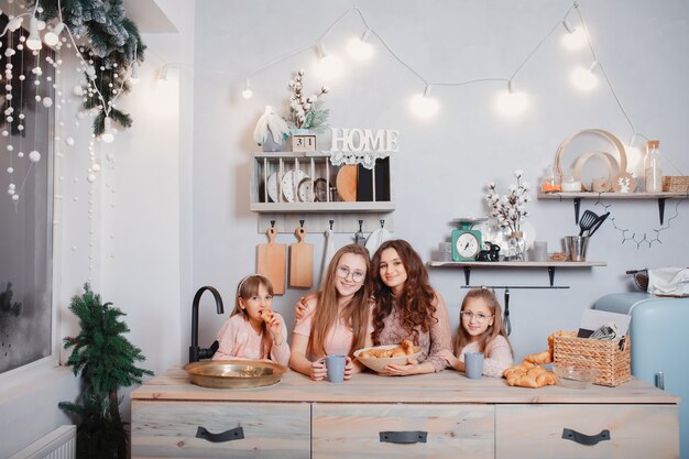 Irmãs bonitos em pé em uma cozinha e come pães