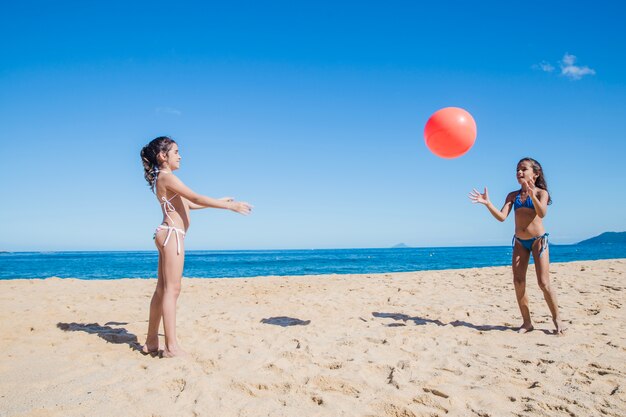 Irmãs brincando com bola na praia