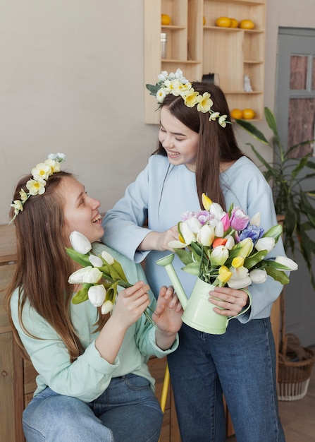 Foto grátis irmãs jovens segurando flores e olhando uns aos outros