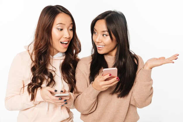 Irmãs muito felizes asiáticas senhoras conversando por telefones móveis.