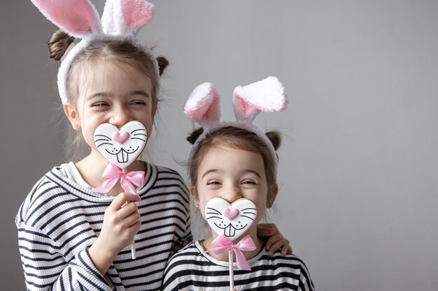 Irmãs pequenas engraçadas com pão de mel da Páscoa em forma de carinhas de coelho e com orelhas de coelho.