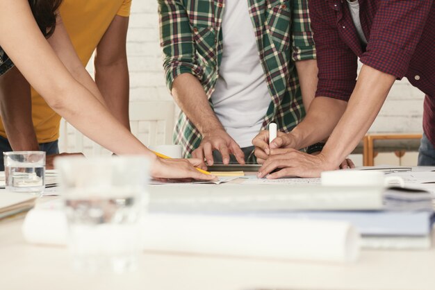 Irreconhecível pessoas vestidas casualmente em pé ao redor da mesa e brainstorming