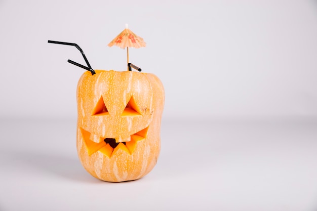 Jack-o-lantern decorado com guarda-chuva e palha