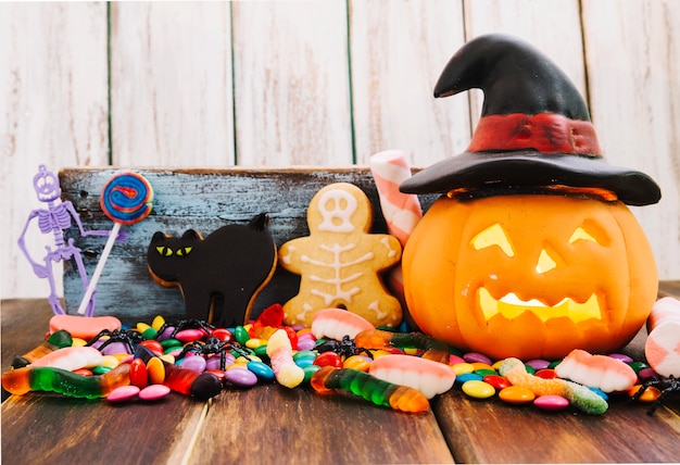 Jack-o-lantern em chapéu de bruxa e doces de Halloween