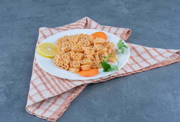 Jantar caseiro com macarrão em forma de coração no prato branco.