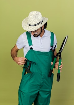 Jardineiro confiante usando óculos ópticos e chapéu de jardinagem Foto gratuita