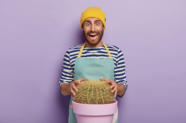 Jardineiro encantado posando com um grande cacto em um vaso