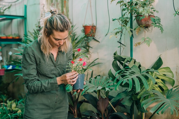 Jardineiro feminino loira cuidando de plantas com flores no berçário