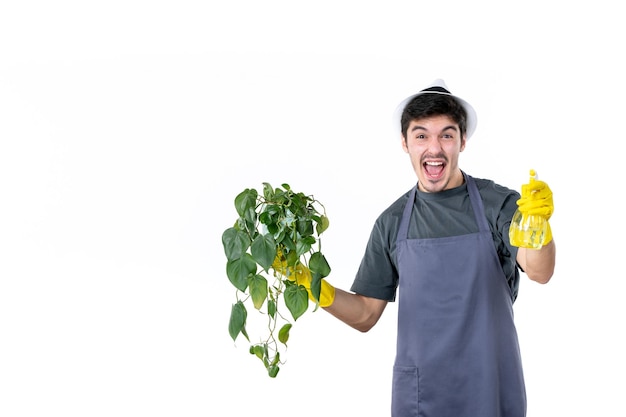 Jardineiro masculino de vista frontal segurando planta em vaso e spray em fundo branco árvore de trabalho cor de grama terra trabalho arbusto de flores