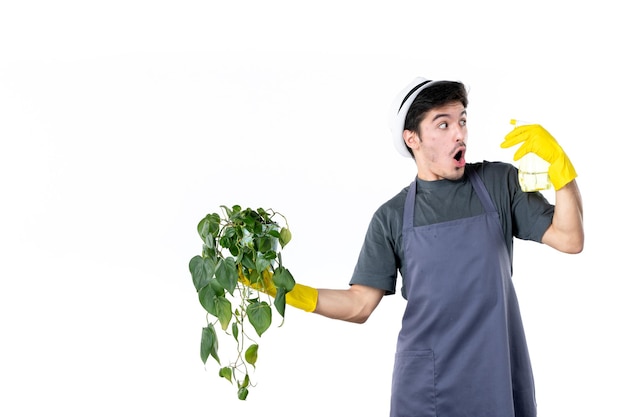 Jardineiro masculino de vista frontal segurando planta em vaso e spray em fundo branco árvore de trabalho grama arbusto cor terra trabalho jardim flor