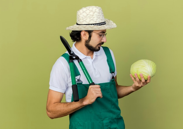 Jardineiro satisfeito usando óculos óticos e chapéu de jardinagem segurando uma tesoura