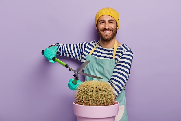 Jardineiro sorridente posando com um grande cacto em um vaso