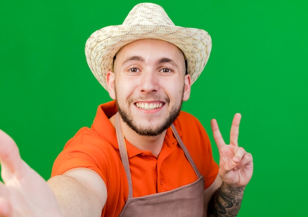 Jardineiro sorridente usando chapéu de jardinagem gesticulando sinal de vitória