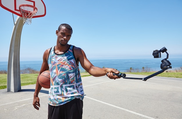 Foto grátis jogador de basquete à beira-mar com câmera selfie