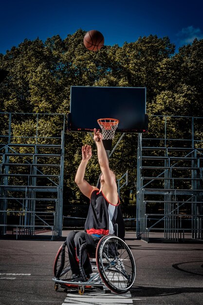 Foto grátis jogador de basquete aleijado em cadeira de rodas joga em um campo de jogo aberto.