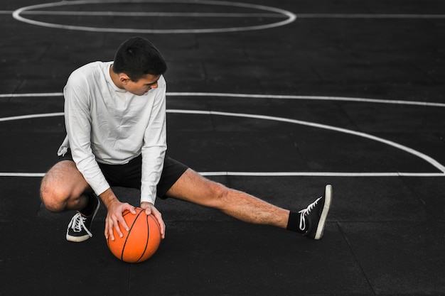 Jogador de basquete, estendendo-se na quadra