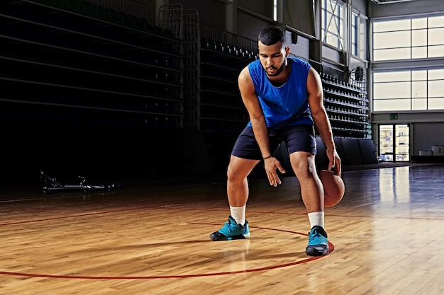 Jogador de basquete profissional negro em ação em um campo de basquete.