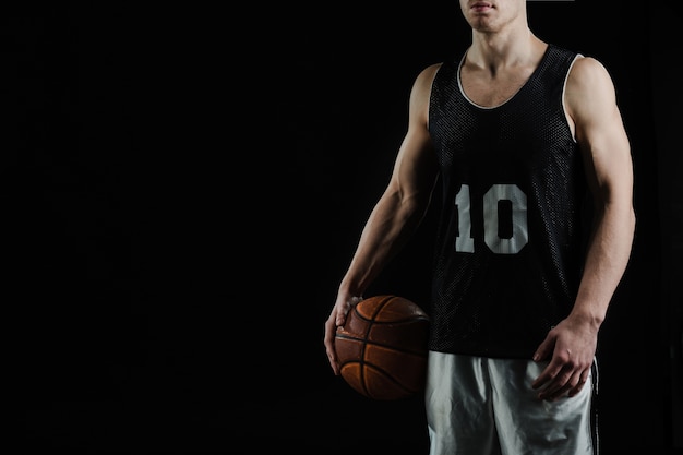 Jogador de basquete profissional segurando a bola debaixo do braço