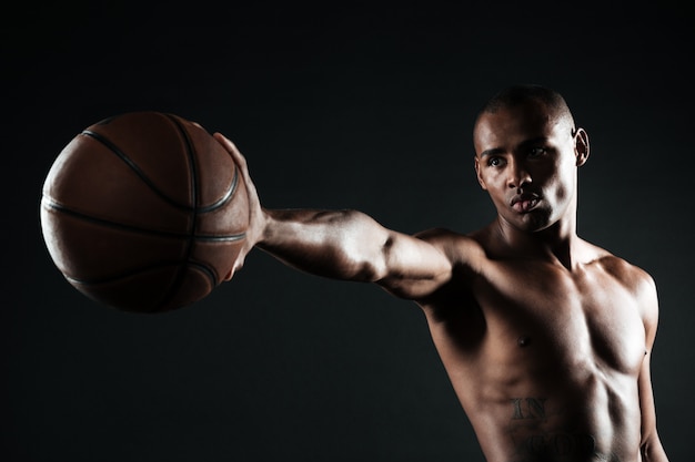 Jogador de basquete sério jovem segurando uma bola com uma mão