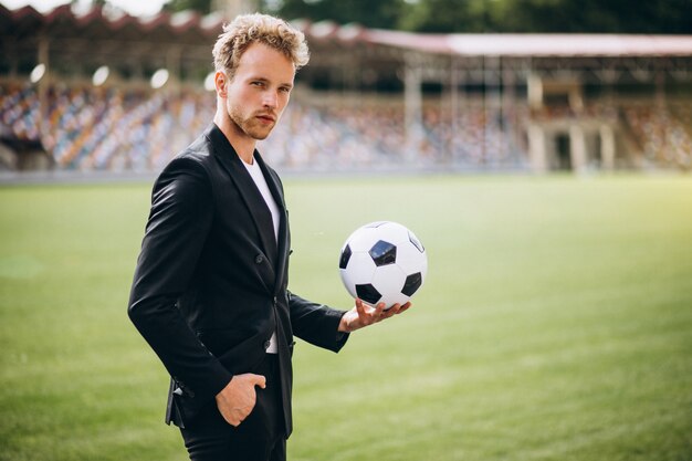 Jogador de futebol bonito no estádio em terno de negócio