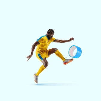 Jogador de futebol chutando a fita adesiva como uma bola no fundo azul. copyspace para sua proposta. design moderno. arte contemporânea, colagem. conceito de esporte, escritório, trabalho, sonhos, negócios, ação.