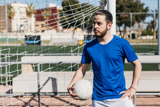 Jogador de futebol com a bola ao lado do gol