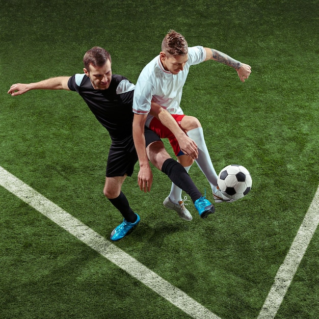 Jogador de futebol, enfrentando a bola sobre o fundo da grama verde.