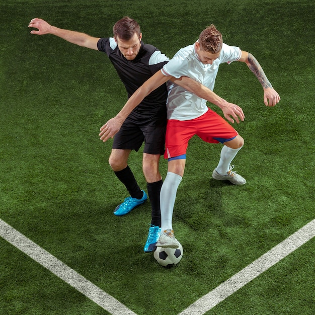 Jogador de futebol, enfrentando a bola sobre o fundo da grama verde.