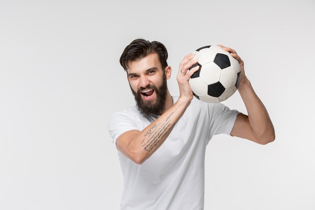 Jogador de futebol jovem com bola na frente da parede branca