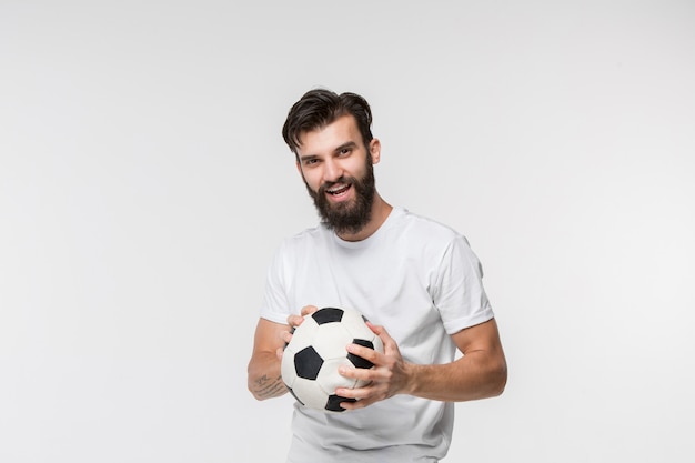 Jogador de futebol jovem com bola na frente da parede branca