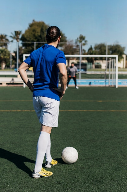 Jogador de futebol, olhando em direção a meta