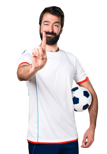 Jogador de futebol segurando uma bola de futebol contando um