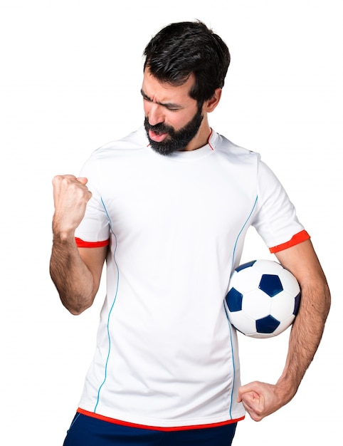 Jogador de futebol sortudo segurando uma bola de futebol
