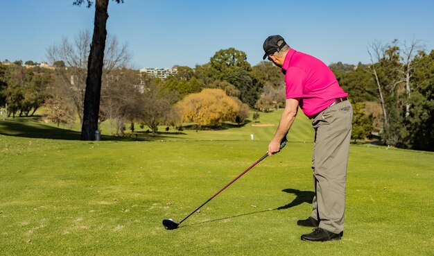 Jogador de golfe profissional jogando com um taco de golfe no campo coberto de grama