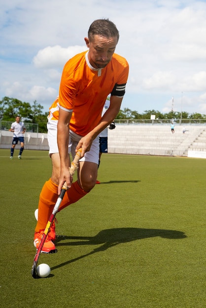 Jogador de hóquei em campo treinando e praticando o esporte na grama