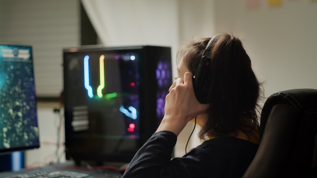 Jogador profissional de eSport com fone de ouvido jogando em videogames competitivos em torneios de jogos cibernéticos. Campeonato virtual no ciberespaço, jogador de esports atuando em um poderoso computador pessoal RGB