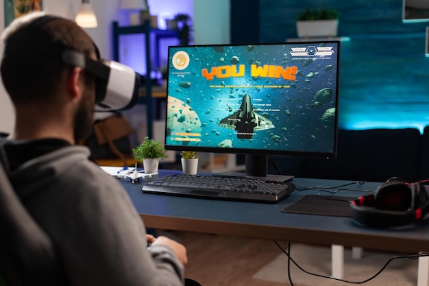 Jogador usando óculos vr para ganhar videogames no computador. Homem com controlador e fone de ouvido de realidade virtual jogando jogo para se divertir com a atividade moderna. Gamer vencedora da competição online