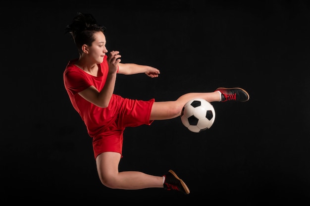 Foto grátis jogadora pulando e chutando bola